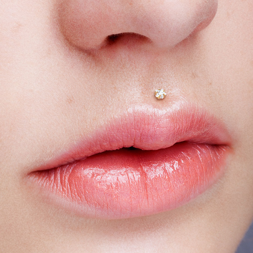 Labret met goudkleurige ster op BioFlex staaf – voor helix of tragus. Sfeerbeeld medusa.