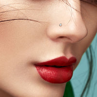Model draagt een subtiele Bioflex neuspiercing met helder kristal, passend bij een minimalistische stijl